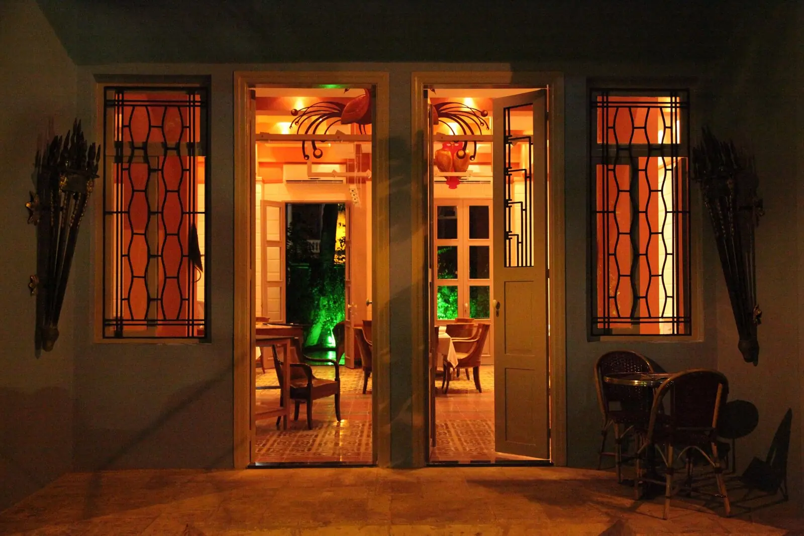 Façade illuminée à la tombée de la nuit, portes ouvertes sur le restaurant