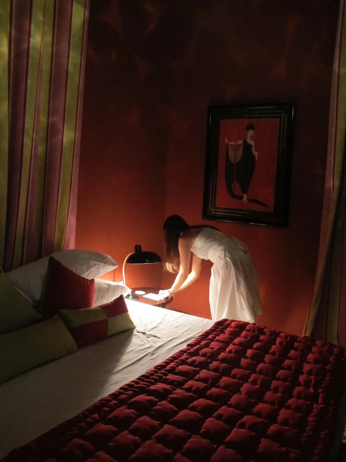 Chambre rouge, couvre-lit capitonné et estampe Art déco, en soirée
