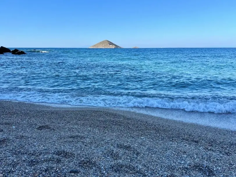Une plage tranquille avec un îlot conique au large